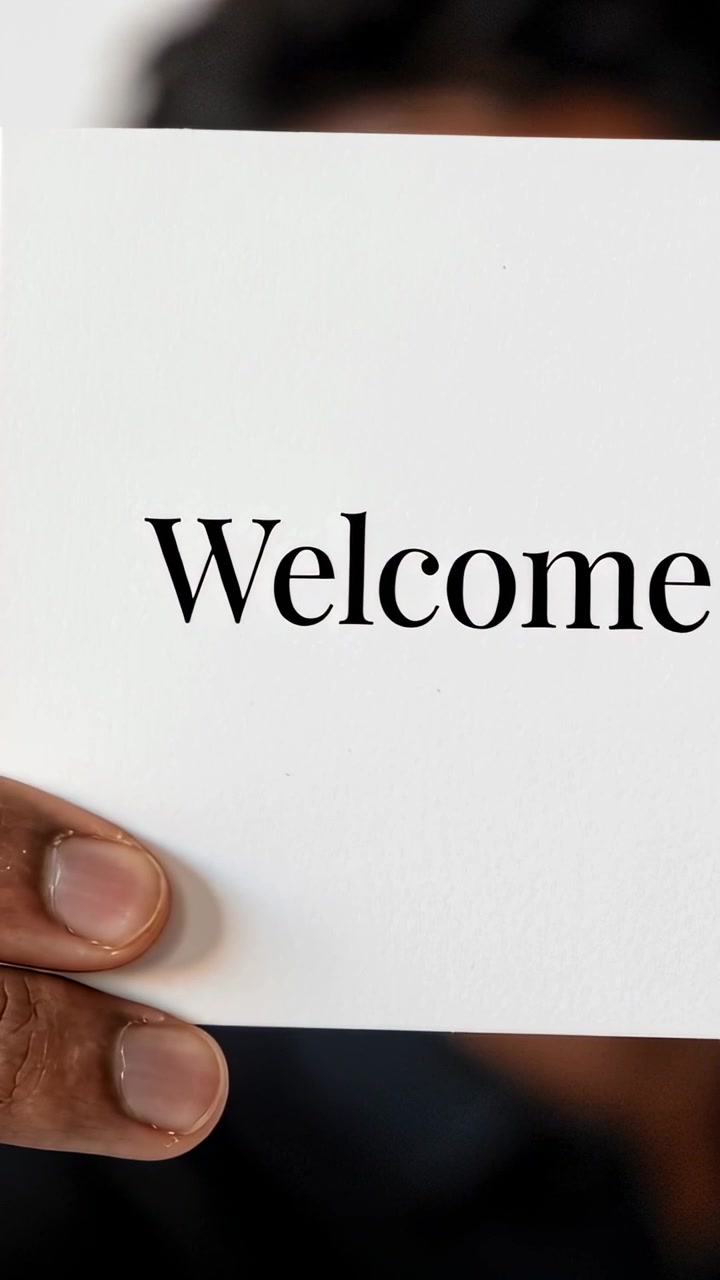 Vertical video: Raising man holding white Welcome card to camera at home, with dark shirt welcoming
