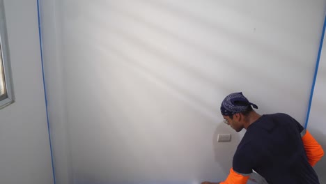 el hombre está aplicando pintura blanca a la pared interior de la casa - toma estática