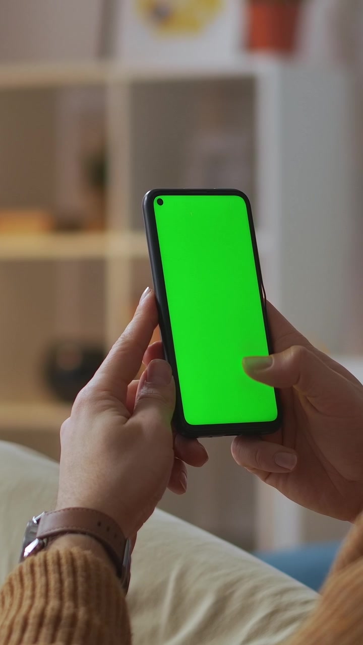 Primo piano di mani che scorrono su smartphone con green screen