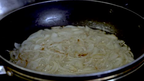 sliced onions being fried and simmering in large pan