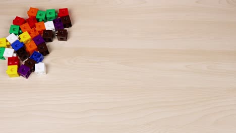 manos organizando cubos coloridos en una mesa de madera