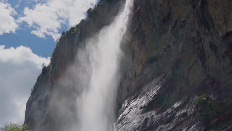 tilt down shot of dramatic giant waterfall flowing in swiss village