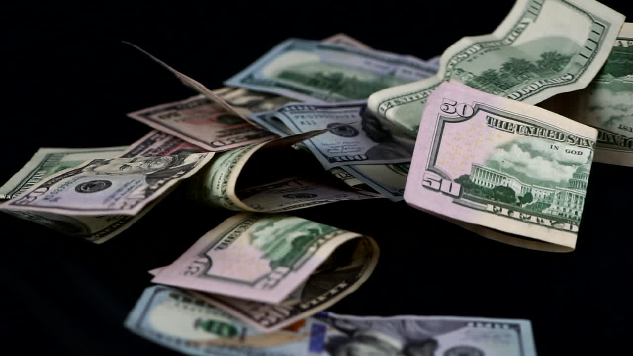 dólares americanos cayendo sobre una mesa negra desde arriba