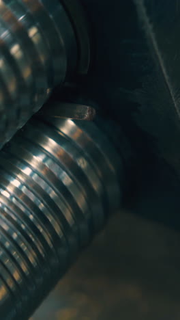 cu shot: skilled jeweler forge-rolls piece of gold metal with modern machine tool on table in light workshop close view