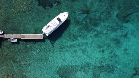 turismo náutico, yate amarrado a un muelle de madera en una laguna azul clara, dron de arriba hacia abajo