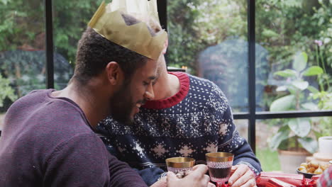 gay male couple sitting around table for christmas dinner talking and making a toast