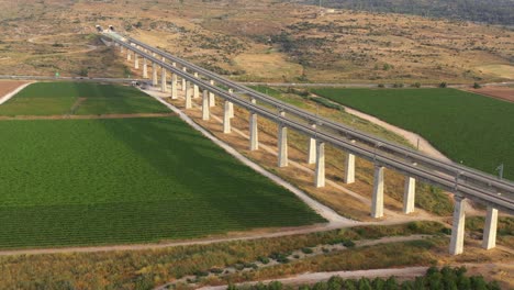 aerial view of elevated train track over vineyards and fields