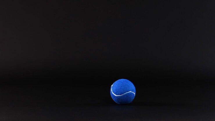 A blue tennis ball rolls across a surface