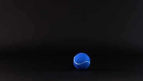 a blue tennis ball rolls across a surface