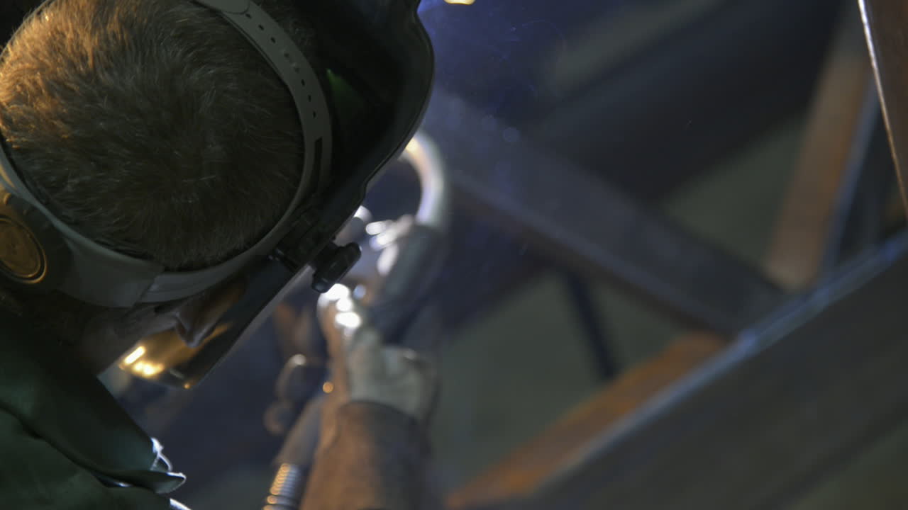 Raw style shot of a man welding steel beams in an industrial machine shop