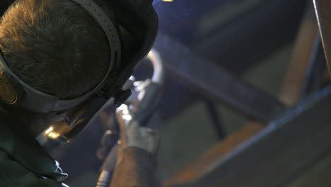 raw style shot of a man welding steel beams in an industrial machine shop