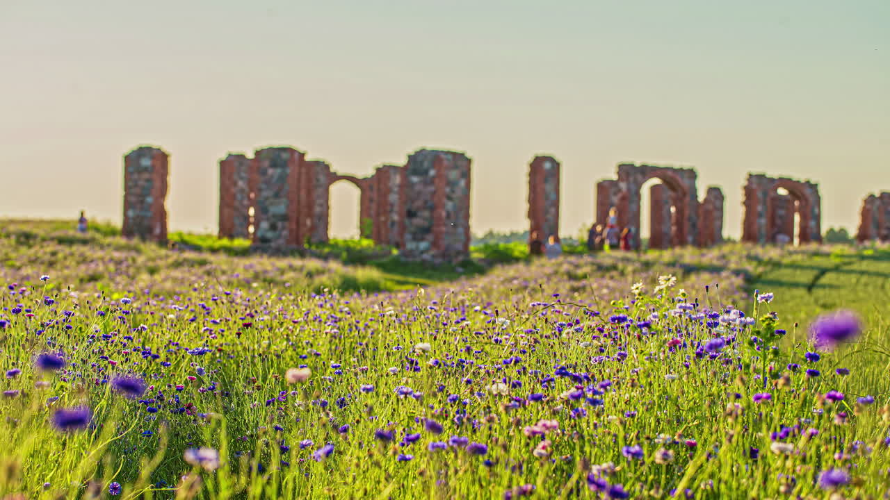 낮에 라트비아에서 중세 성터를 돌아다니는 관광객들의 저속 촬영