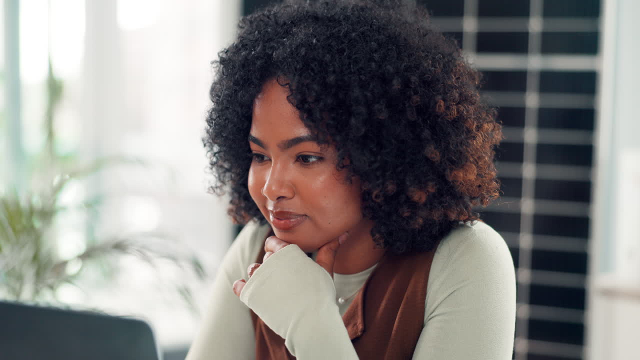 Thoughtful Young Woman Working on Laptop in Modern Office