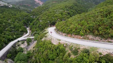 Imágenes-Aéreas-De-Un-Automóvil-Conduciendo-Por-Las-Sinuosas-Carreteras-En-Las-Exuberantes-Montañas-Verdes-De-Albania