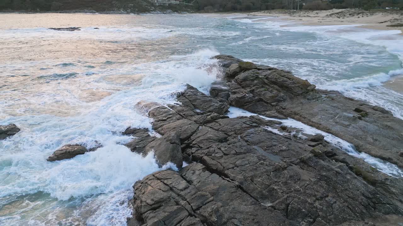 olas chocando contra las rocas de una hermosa playa de arena blanca al atardecer