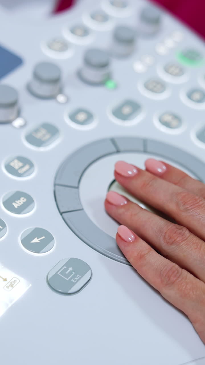 Female medic's hand on the keyboard of ultrasound machine. Doctor is pressing some buttons on the apparatus. Close up. Vertical video