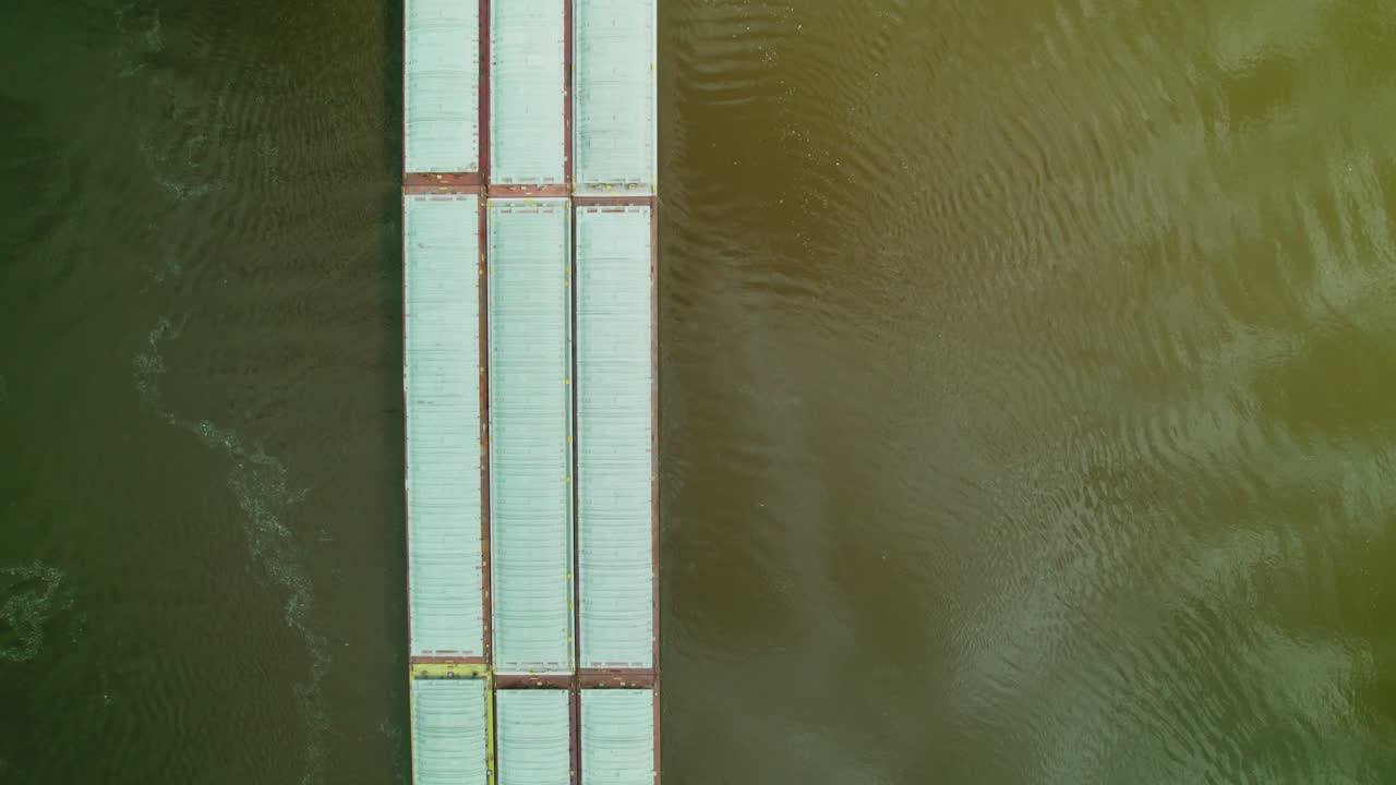 Top-down aerial view of tugboat pushing connected barges on Mississippi River in the USA