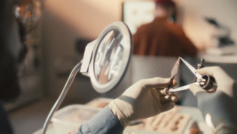 researcher measuring archaeological artifact with caliper under magnifying glass