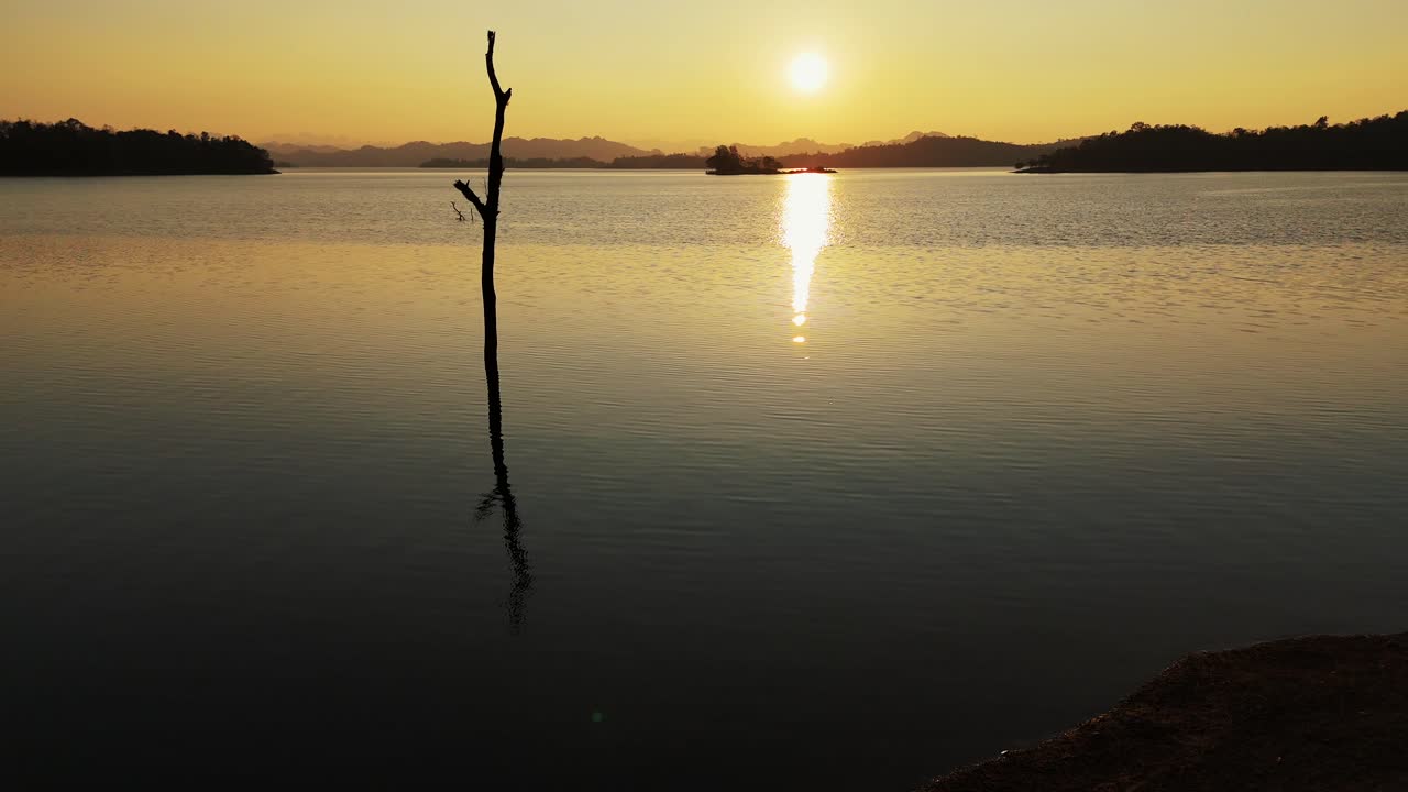 A breathtaking sunset graces the tranquil waters of Vajiralongkorn Lake in Sangklaburi, Thailand