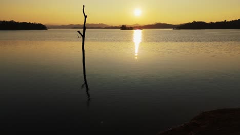 una puesta de sol impresionante adorna las aguas tranquilas del lago vajiralongkorn en sangklaburi, tailandia