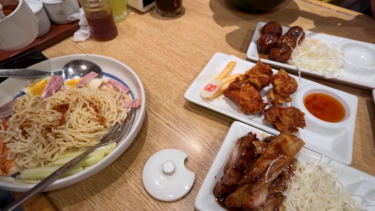 Pengambilan Gambar Sudut Tinggi Mi Ramen, Ayam Goreng, dan Takoyaki di Meja Restoran