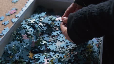 Frau-Sucht-Mit-Der-Hand-In-Einer-Schachtel-Mit-Puzzleteilen-In-Zeitlupe-50i