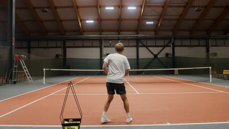 man practicing tennis indoors