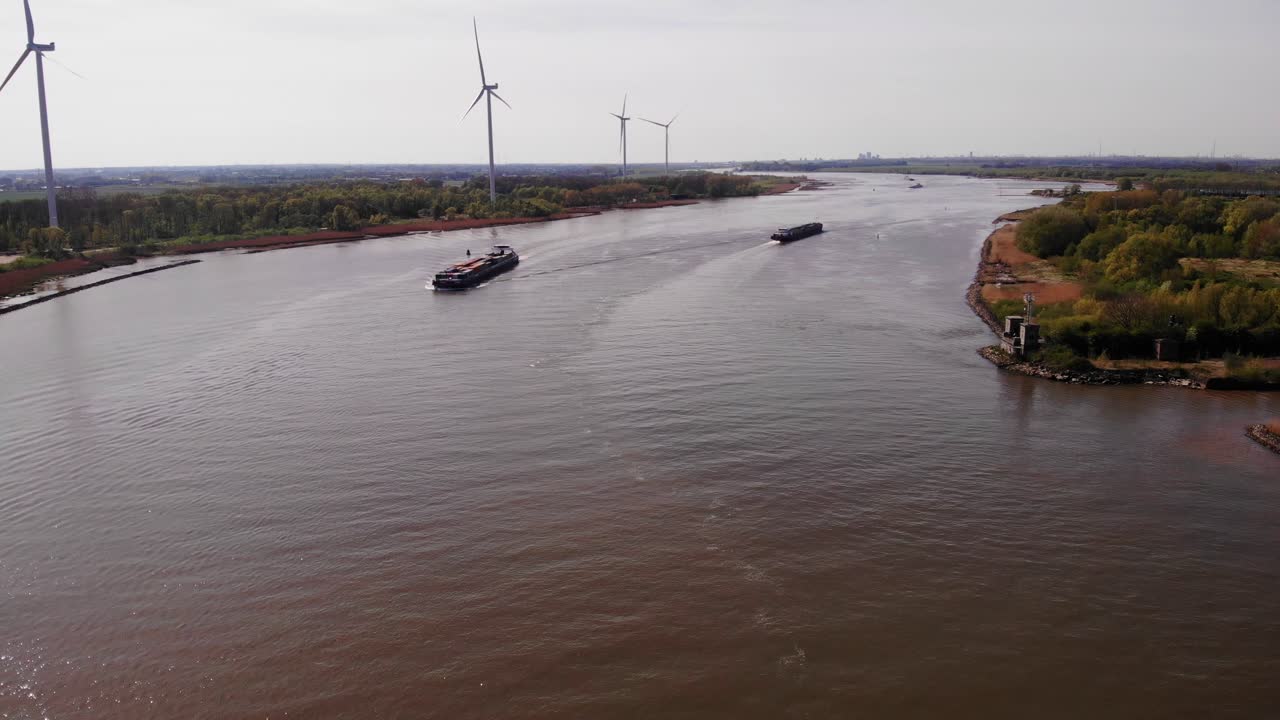 강변 둑에 있는 여전히 풍력 터빈을 지나 항해하는 두 척의 배와 함께 oude maas에 대한 공중 전망