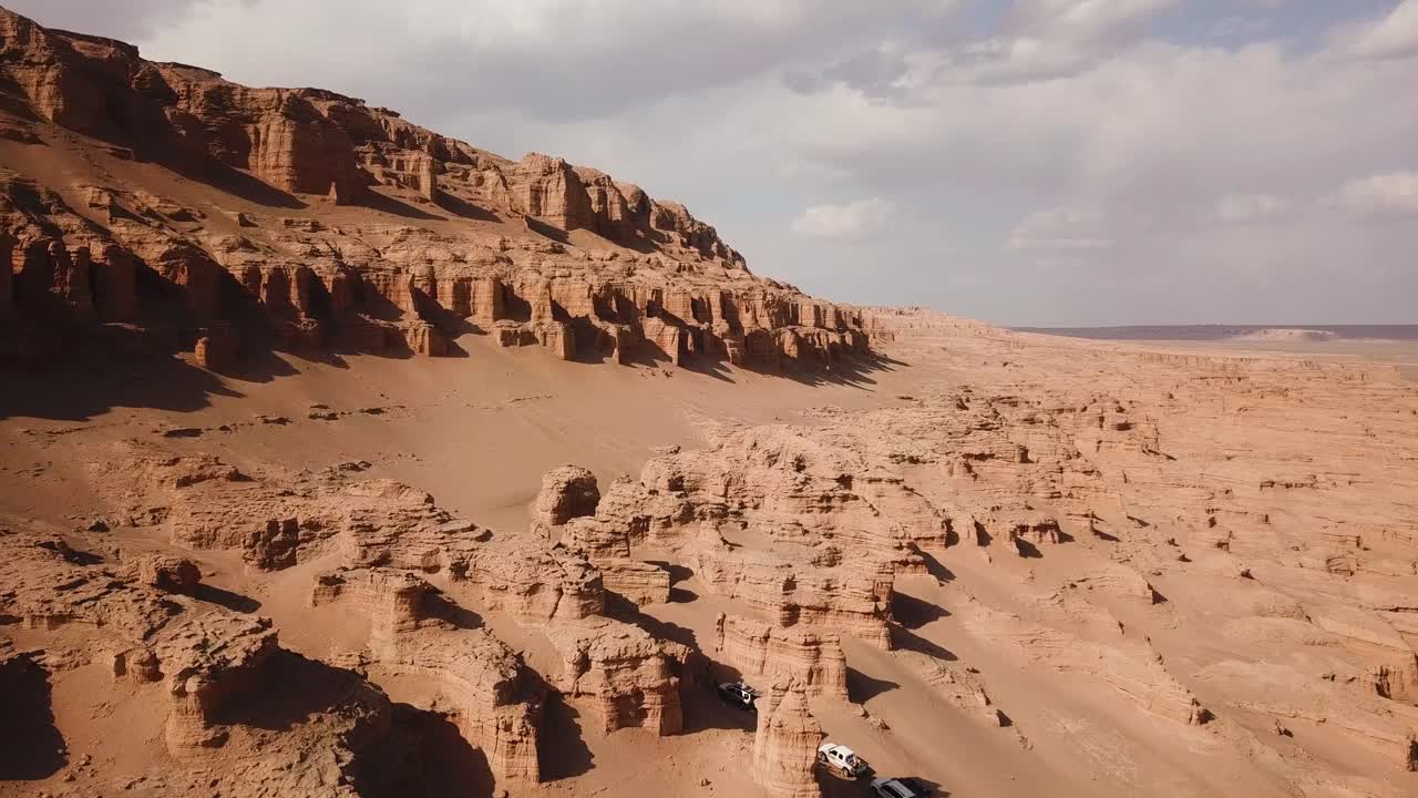 Huge wonderful rock cliff formation kalut in desert climate cloudy weather sand dune background and scenic natural landscape of SUV vehicle off road car adventure traveler in middle east Saudi Iran
