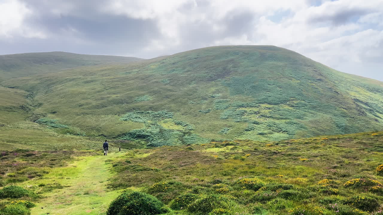 A man walking on the grassaland of conor pass ireland