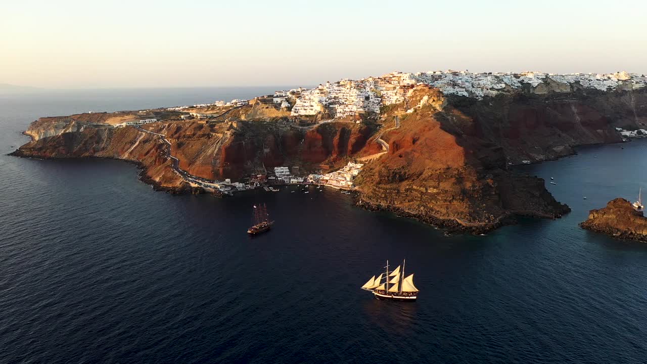 video de vista aérea de hermosos veleros navegando en el profundo mar egeo azul oscuro durante la puesta de sol, santorini, cícladas, grecia