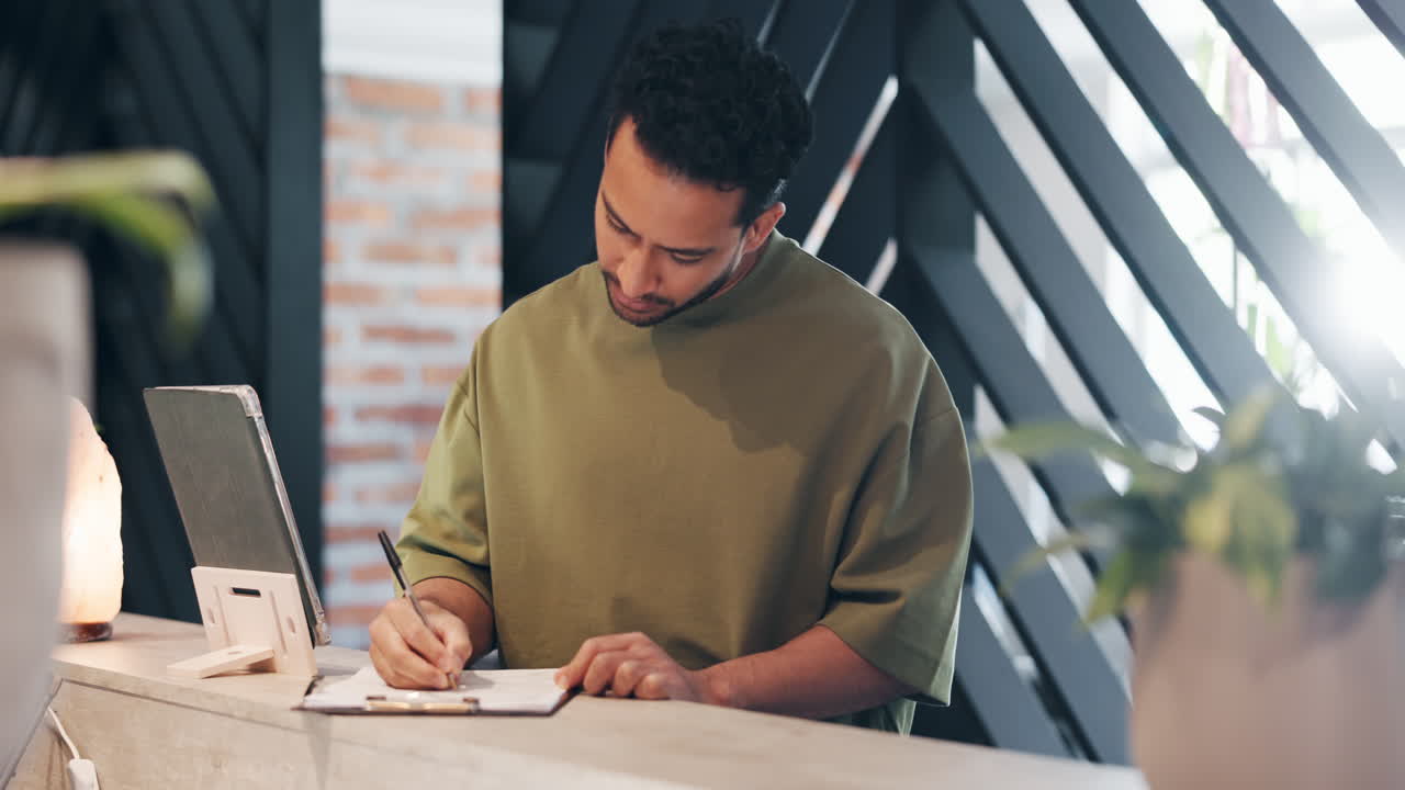 Young Man Writing on Clipboard at a Modern Desk