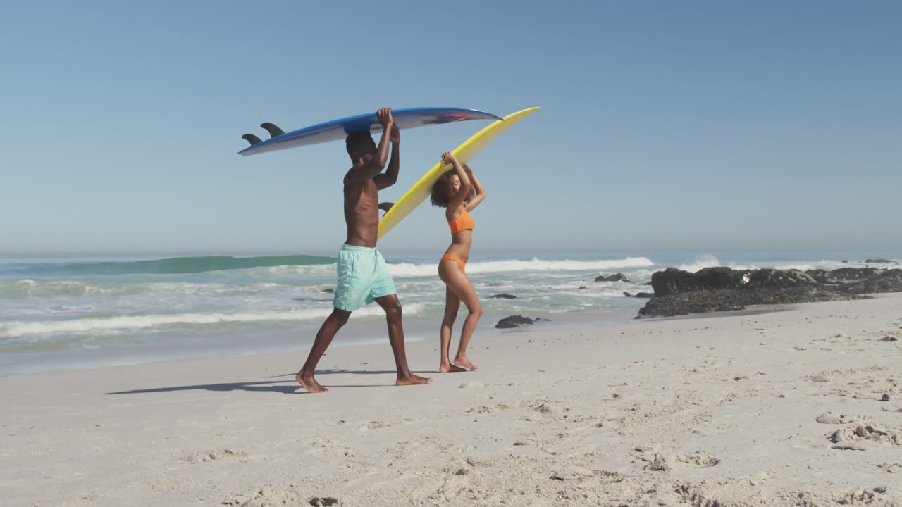African American couple holding surfboards on their heads