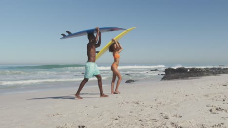 african american couple holding surfboards on their heads