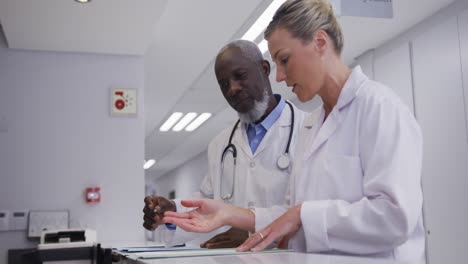 diverse male and female doctors standing at hospital reception and discussing documents