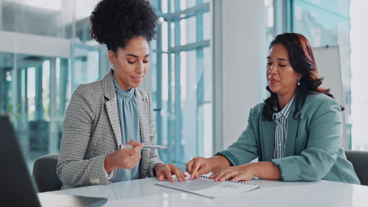 Two businesswomen in a meeting discussing a contract