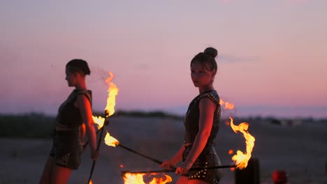 a group of professional circus performers with fire shows dance shows in slow motion using flame-throwers and rotating the torches burning objects.