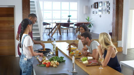 friends talk to guests whilst making food for dinner party