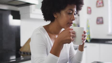 african american woman drinking coffee in the kitchen at home
