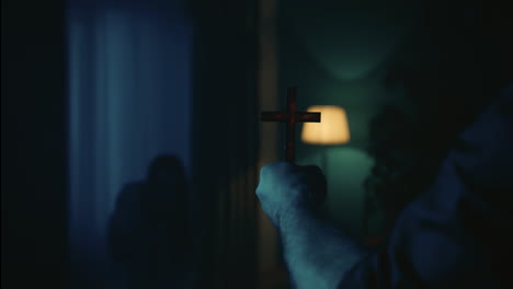 hand holding a cross in a dark room