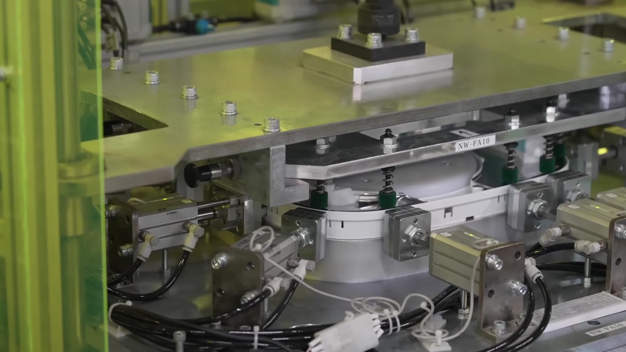 Automated pneumatic press machine with multiple actuators processing rice cooker components on factory floor
