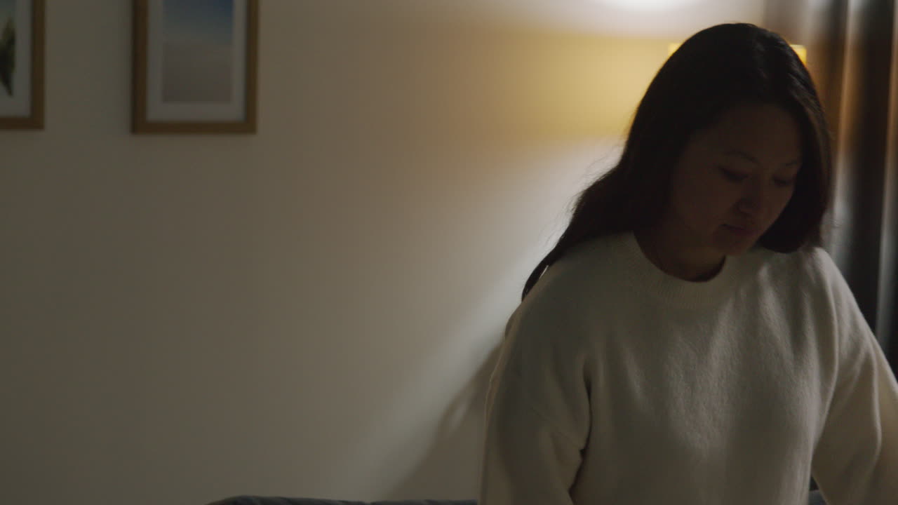 소파에서 집에서 저녁을 보내고 무선 헤드폰을 착용하고 휴대전화에서 음악이나 캐스트를 스트리밍하는 여성 1