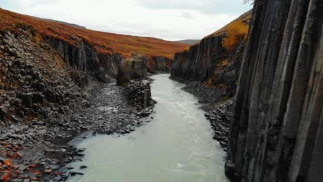 el avión no tripulado vuela sobre el cañón de columnas de basalto negro, islandia