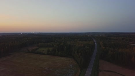 Abendaufnahme-Eines-Waldes-In-Einem-Sonnenuntergang-Mit-Einer-Straße-Und-Einem-Orangefarbenen-Himmel