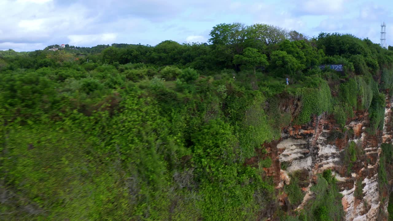 personas disfrutando de la vista desde el acantilado de uluwatu en bali, indonesia - toma aérea de un avión no tripulado