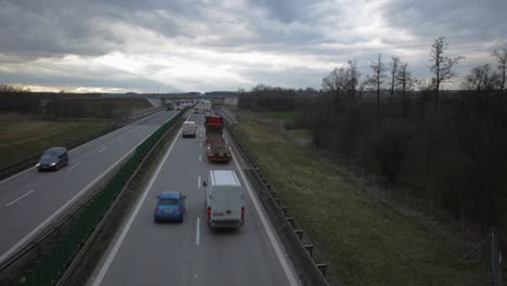 above tilt shot of a busy highway with trucks and cars speeding by