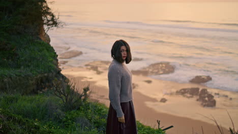 woman relax cloudy seashore. serious thoughtful girl walking to ocean waves.