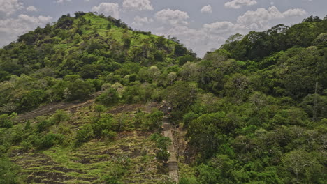 Dambulla-Sri-Lanka-Aerial-v2-low-drone-flyover-Uyanwaththa-Royal-Buddhist-Temple-capturing-golden-Buddha-on-the-hillside-towards-the-Jungle-Isigili-Kanda-mountain---Shot-with-Mavic-3-Cine---April-2023