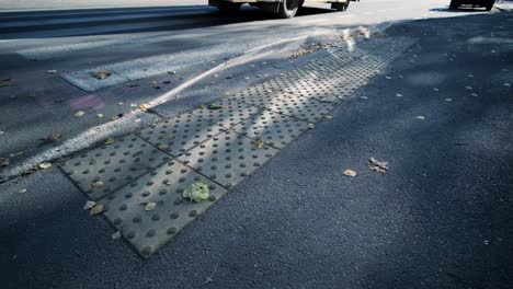 visually impaired man crossing the road with his stick with the help of tactile pedestrian sidewalk for the visually impaired in the city.