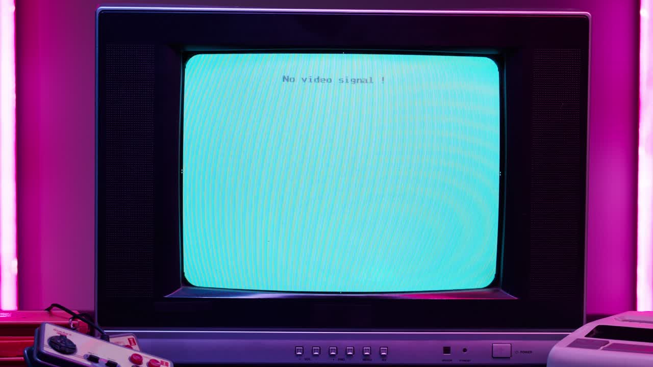 Old television with blue screen on pink neon background. Close-up of vintage tv and cartridges for retro playstation. Antique video game, nostalgia